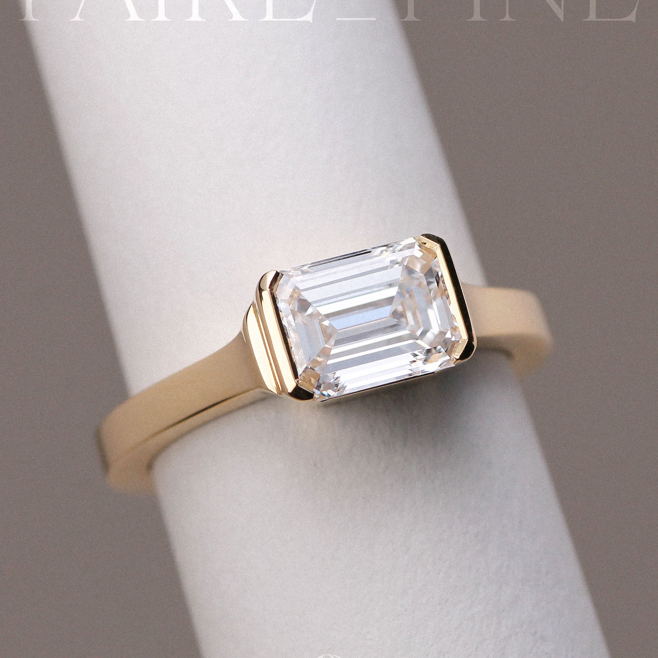 East-West emerald cut diamond engagement ring set in gold